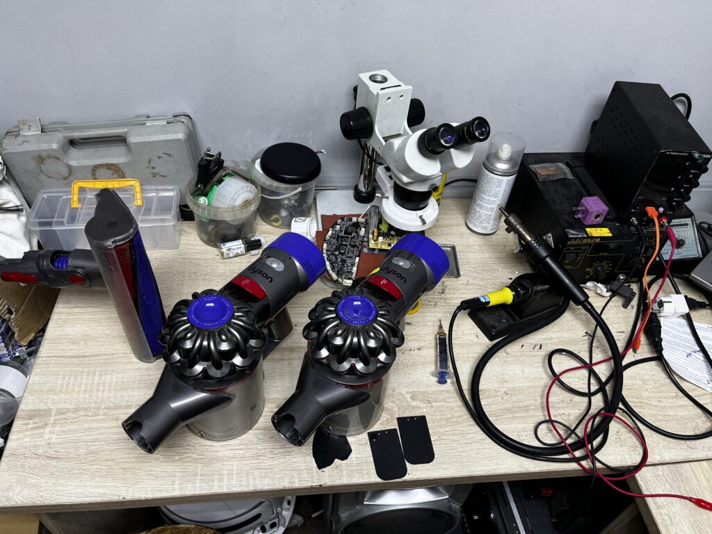 Два пылесоса Dyson V-серии, плата и микроскоп на столе мастера в Митино